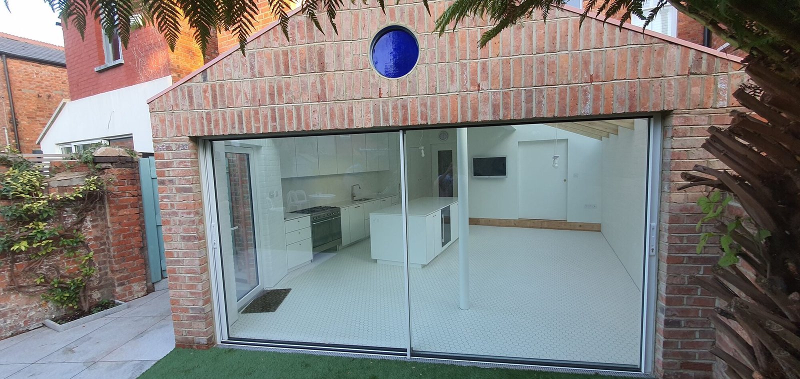 Round blue stained-glass window set into reclaimed brickwork, Camden